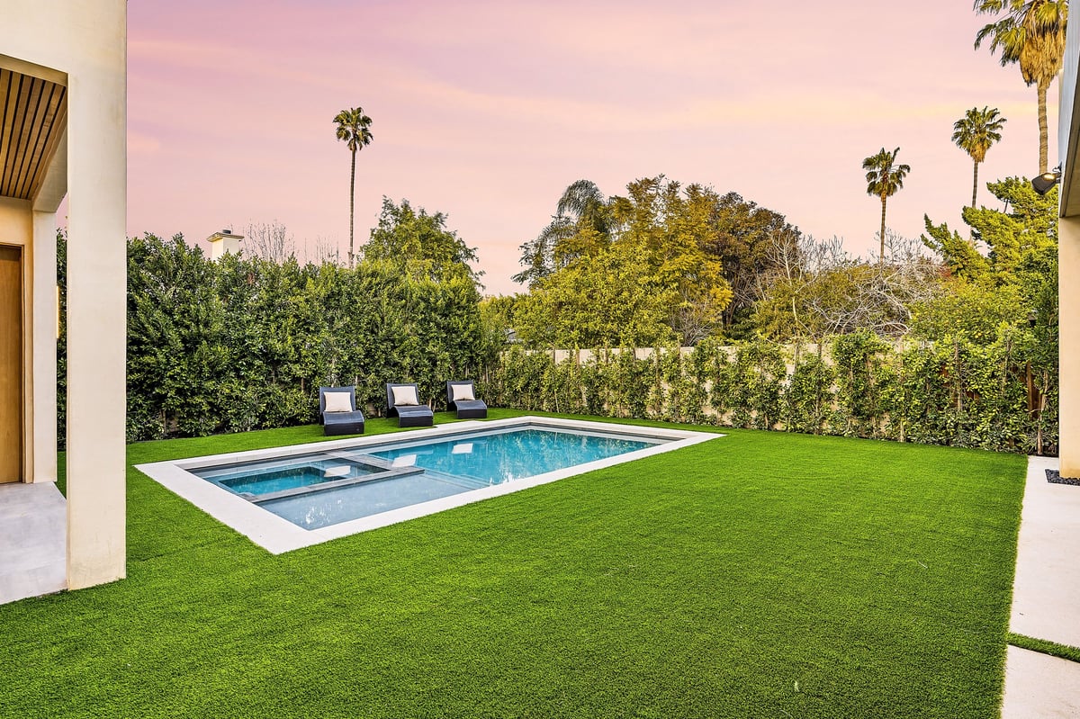 Giardino curato con piscina, lettini e verde lussureggiante al tramonto