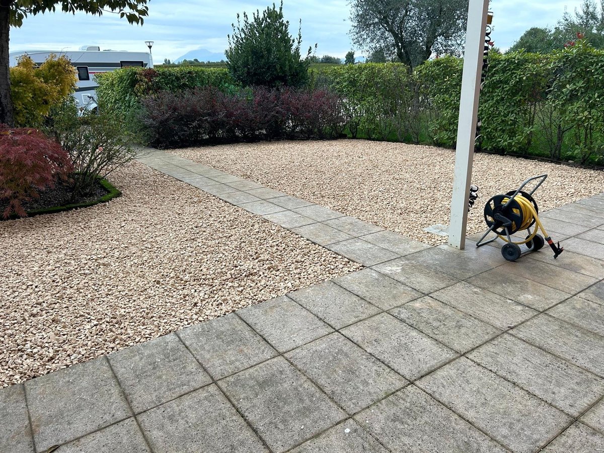 Patio moderno con lastre grigie che si apre su un giardino in ghiaia circondato da siepi