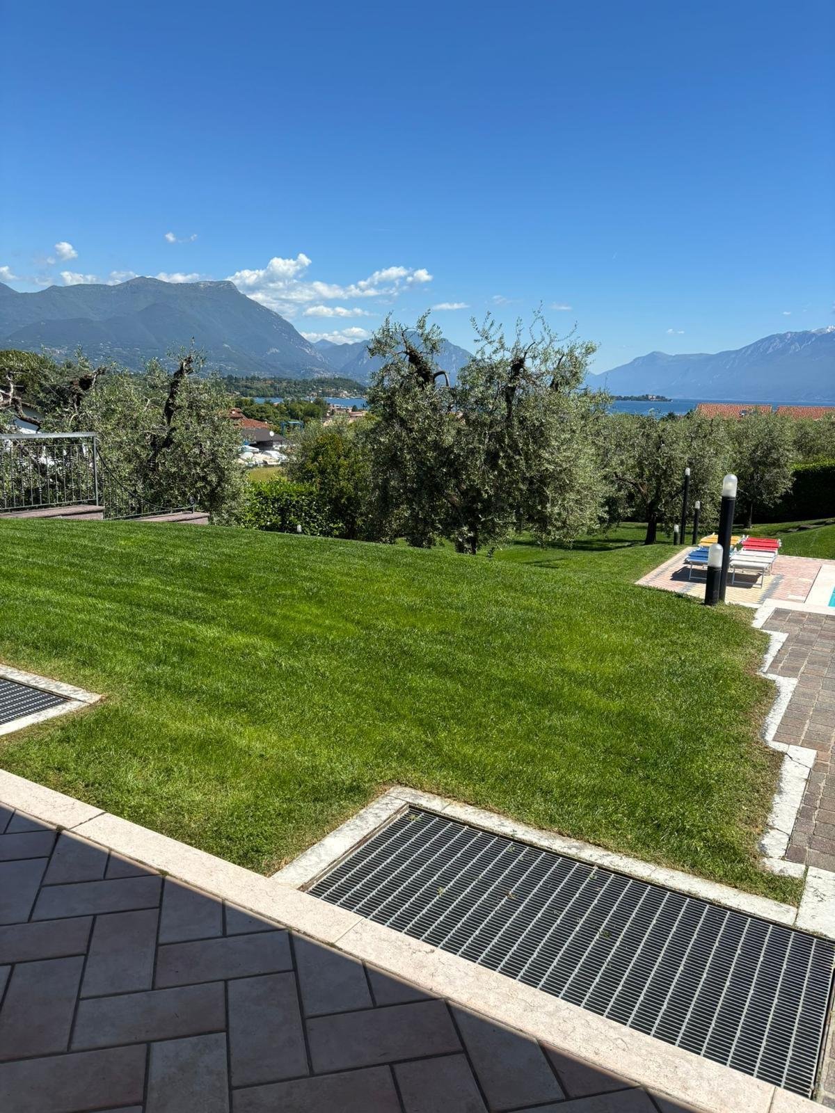 Prato ampio con ulivi affacciato sulle montagne e sul lago, con terrazza in primo piano