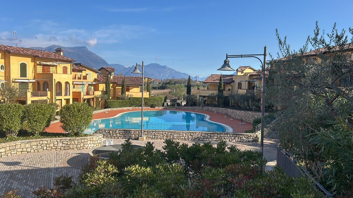 Residence con piscina, ville gialle in stile mediterraneo e montagne sullo sfondo