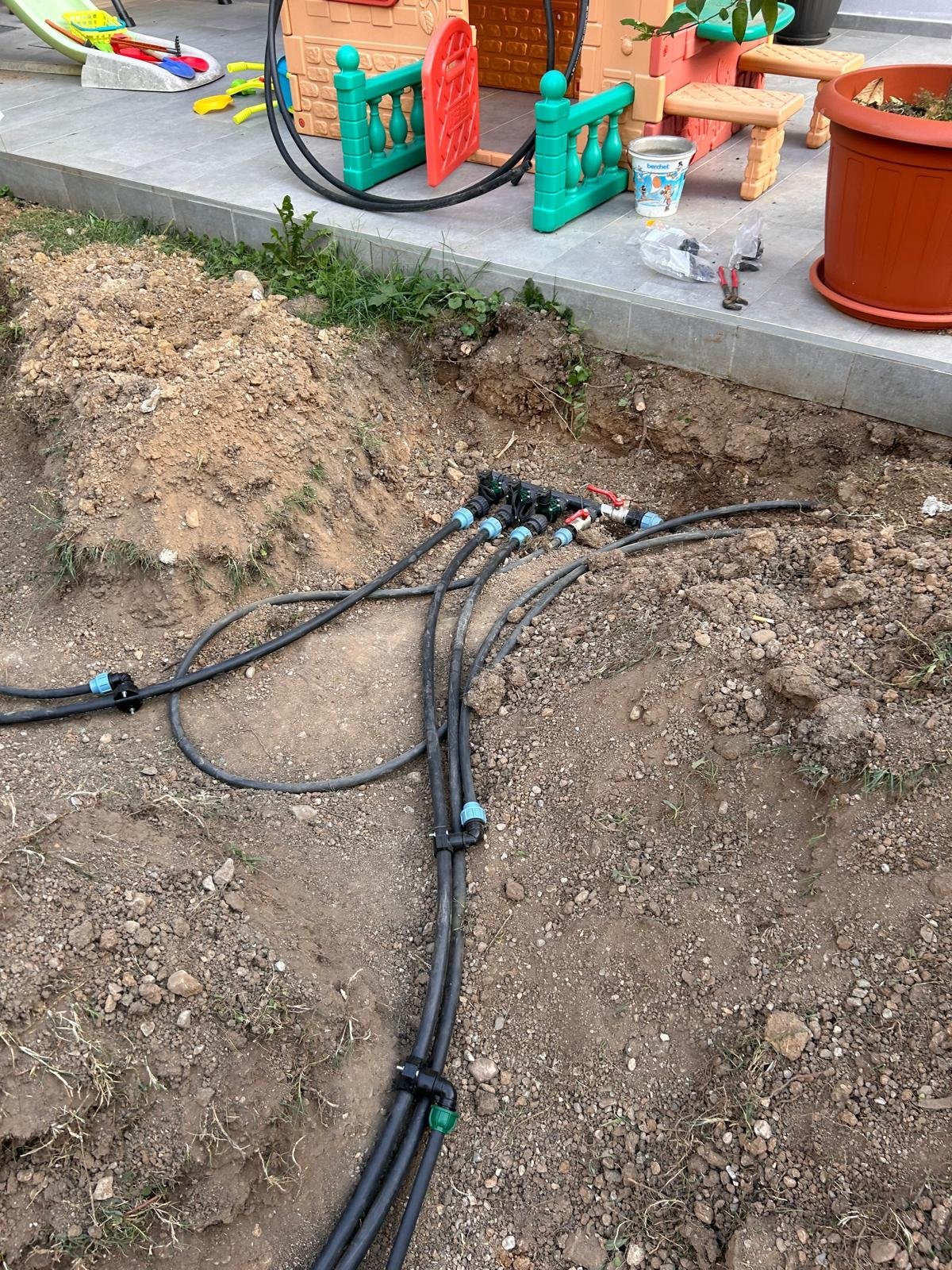 Tubi e raccordi per impianto di irrigazione posati nel terreno vicino a un patio