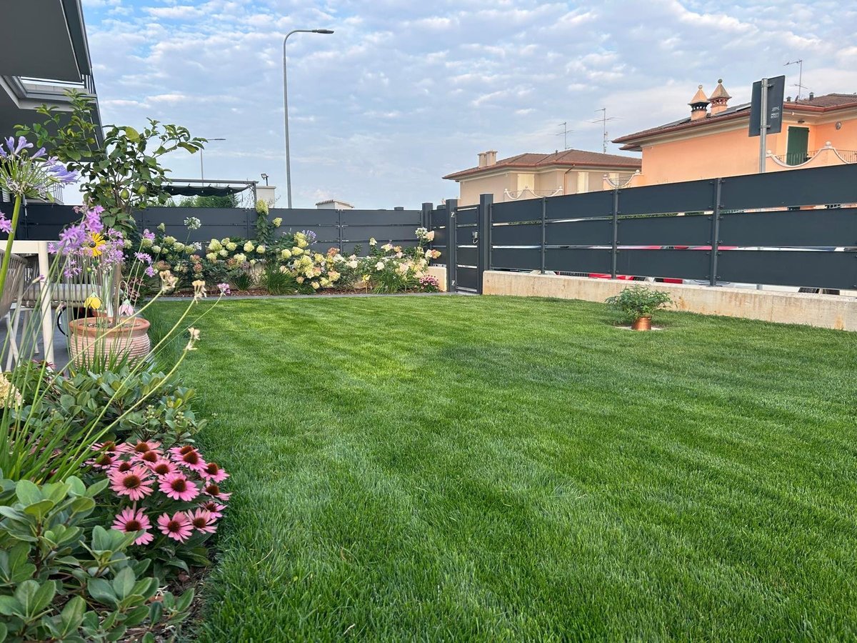 Giardino residenziale curato con prato all'inglese e piante fiorite lungo il bordo